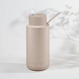 Beige water bottle with straw lid on a light background