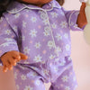 Close-up of a doll wearing a purple outfit with floral patterns on a light background