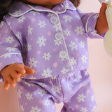Close-up of a doll wearing a purple outfit with floral patterns on a light background