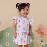 Young girl wearing a floral dress with fairy design against a floral background