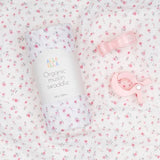 Organic muslin swaddle with pink floral pattern on a matching pink bow, branded 'Alla Ella'.