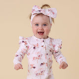 Baby wearing a floral outfit and headband on a beige background
