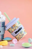 Colorful tumbler with a lid and straw on a pink background