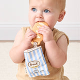 Baby holding a cookie with a toy shaped like a bread bag