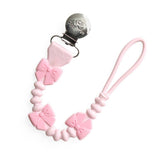 Pink pacifier clip with bow designs on a white background