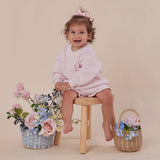 Child sitting on a stool with flowers and a basket on a beige background