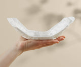 Hand holding a white diaper against a beige background