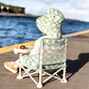 Child sitting in a green checkered chair by a waterfront