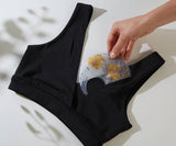 Person using a floral-patterned tool on black underwear against a light background