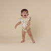 Child wearing a colorful onesie with a lemon pattern on a beige background