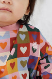 Child wearing a colorful patterned shirt with hearts and flowers.