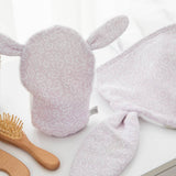 Floral-patterned bunny-shaped towel with a wooden hairbrush on a white surface