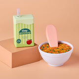 Bowl of soup with a popsicle and 'tiny tummies' juice box on a peach background