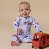 Baby in a fire truck-themed onesie with a toy truck on a beige background