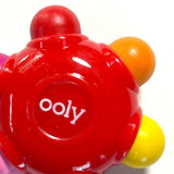 Red toy with colorful spheres and 'ooly' branding on a white background