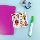 Sheet of stickers with cartoon characters next to a purple notebook and green marker on a light blue background