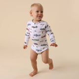 Baby wearing a long-sleeve onesie with car pattern on a beige background
