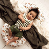 Baby lying on a cushion with a striped outfit and green shorts