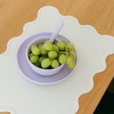 Bowl of green grapes on a decorative plate with a wooden table background
