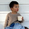 Child holding a cup against a white wooden background