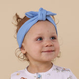 Child wearing a blue headband against a beige background