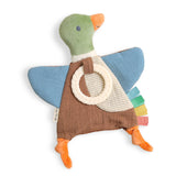 A duck-shaped fabric baby teething toy with a green head, blue wings, brown body, orange beak and feet, a cream ring handle, and multicolor feather tabs, shown on a white background.