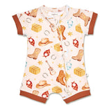 A baby short-sleeve romper with a western-themed print featuring cowboy boots, hats, bandanas, guitars, and stacked boxes on a cream background, finished with brown ribbed trim.