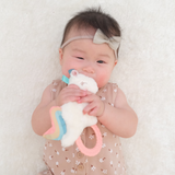 Baby holding a soft toy with colorful rings on a white background