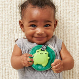 Baby holding a green toy with a frog design on a textured white background