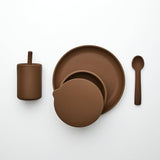 Brown ceramic tableware set including plates, a cup, and a spoon on a white background