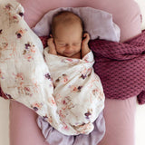 Newborn baby wrapped in a floral blanket on a pink surface