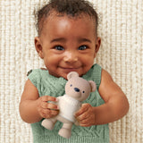 Baby holding a teddy bear against a textured beige background