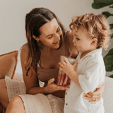 Woman and child sitting together, with the child holding a drink.