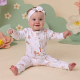 Baby in a floral outfit with a headband sitting on a floral background