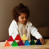 Child playing with colorful triangular blocks on a wooden table