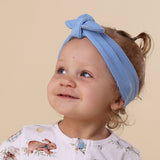 Child wearing a blue headband with a beige background