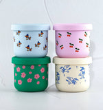 Four colorful containers with animal and floral patterns on a white background