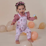 Child in a pink outfit with balloon decorations on a beige background