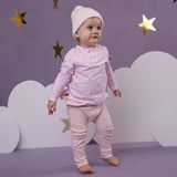 Child wearing a pink outfit with stars against a purple background with stars and clouds