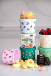 Stack of colorful snack pots with snacks and fruits on a light background