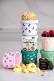 Stack of colorful snack pots with snacks and fruits on a light background