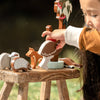 Child playing with wooden animal toys on a wooden stool outdoors.