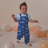 Child wearing a blue patterned outfit with balloons in the background