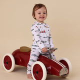 Child sitting on a red toy car with a beige background
