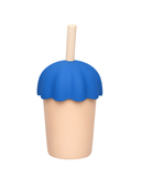Beige cup with blue silicone sleeve and wooden straw on a white background