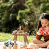 Child sitting outdoors with a miniature table and tea set