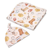 A folded and flat-laid baby gift set featuring a soft cloth pouch and a matching baby hat. The set has a light pink background with a western-themed print including brown cowboy boots, tan hats, a guitar, horseshoes, and stars.