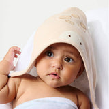 Baby wearing a beige hooded towel with cut-out patterns on a white background