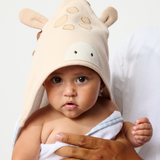 Baby wearing a giraffe-themed hooded towel with a person holding them, on a plain background