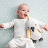 Baby lying on a light blue patterned surface with a plush toy